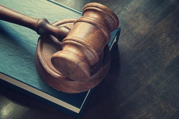 Wooden gavel on law book, symbolizing justice, against a textured, softly lit wooden backdrop.