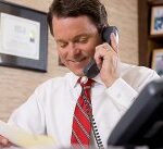 Professional man discusses work on phone in well-organized, personalized office space.