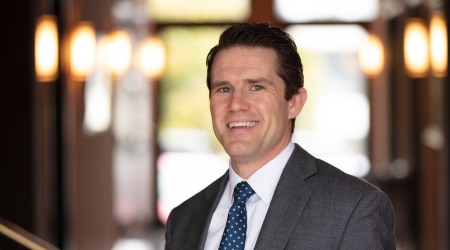 Confident middle-aged businessman in pinstriped suit smiling in a professional office setting.