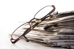 Reading glasses on a stack of newspapers, symbolizing intellectual pursuit and information engagement.