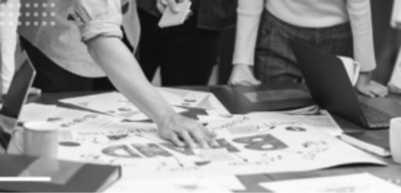 Team discussing over blueprint in a grayscale collaborative workspace photo.