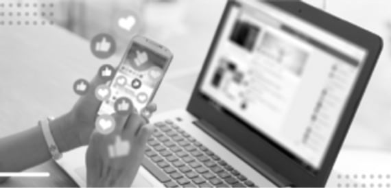 Hands holding smartphone with social media icons, blurred laptop in background, symbolizing digital connectivity.