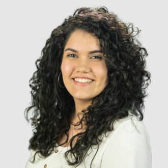 Portrait of rhina gutierrez smiling warmly, curly black hair, light top, friendly and confident.