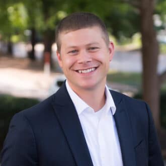 Professional headshot of tanner jones, smiling in a navy blazer and white shirt.