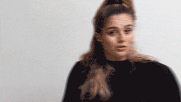 GIF of woman in turtleneck reacting with surprise and confusion in conversation.