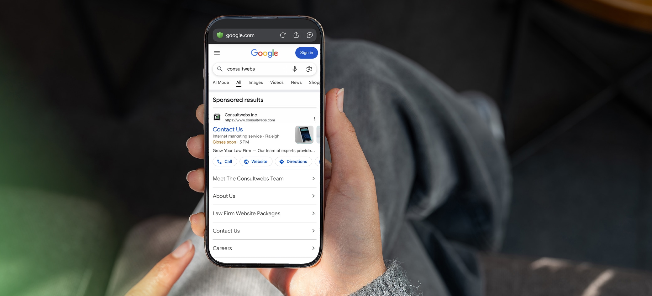 Hand holding smartphone showing political news article on app, with social interaction options.